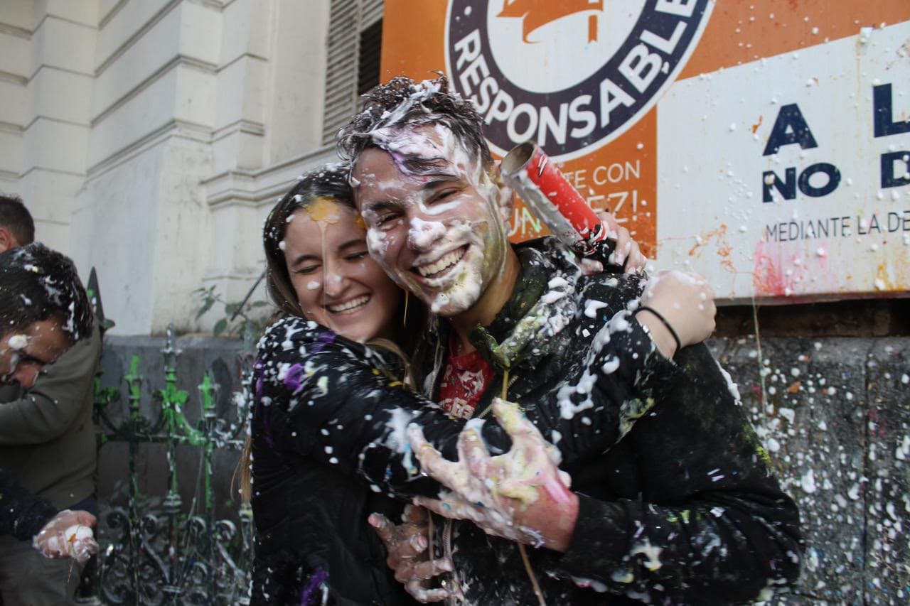 Yesu y Juli abrazados, celebrando entre la espuma